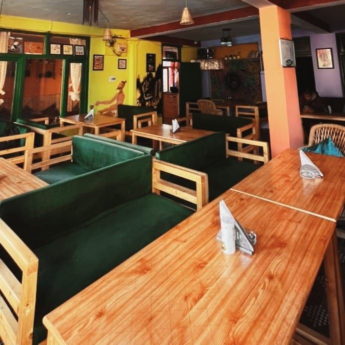 Dining room with green sofas and long pine tables