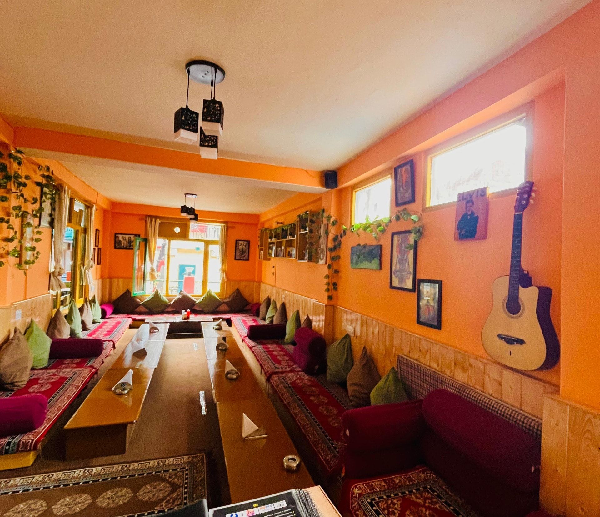 Orange lounge with floor seating, rugs, cushions and a guitar on the wall