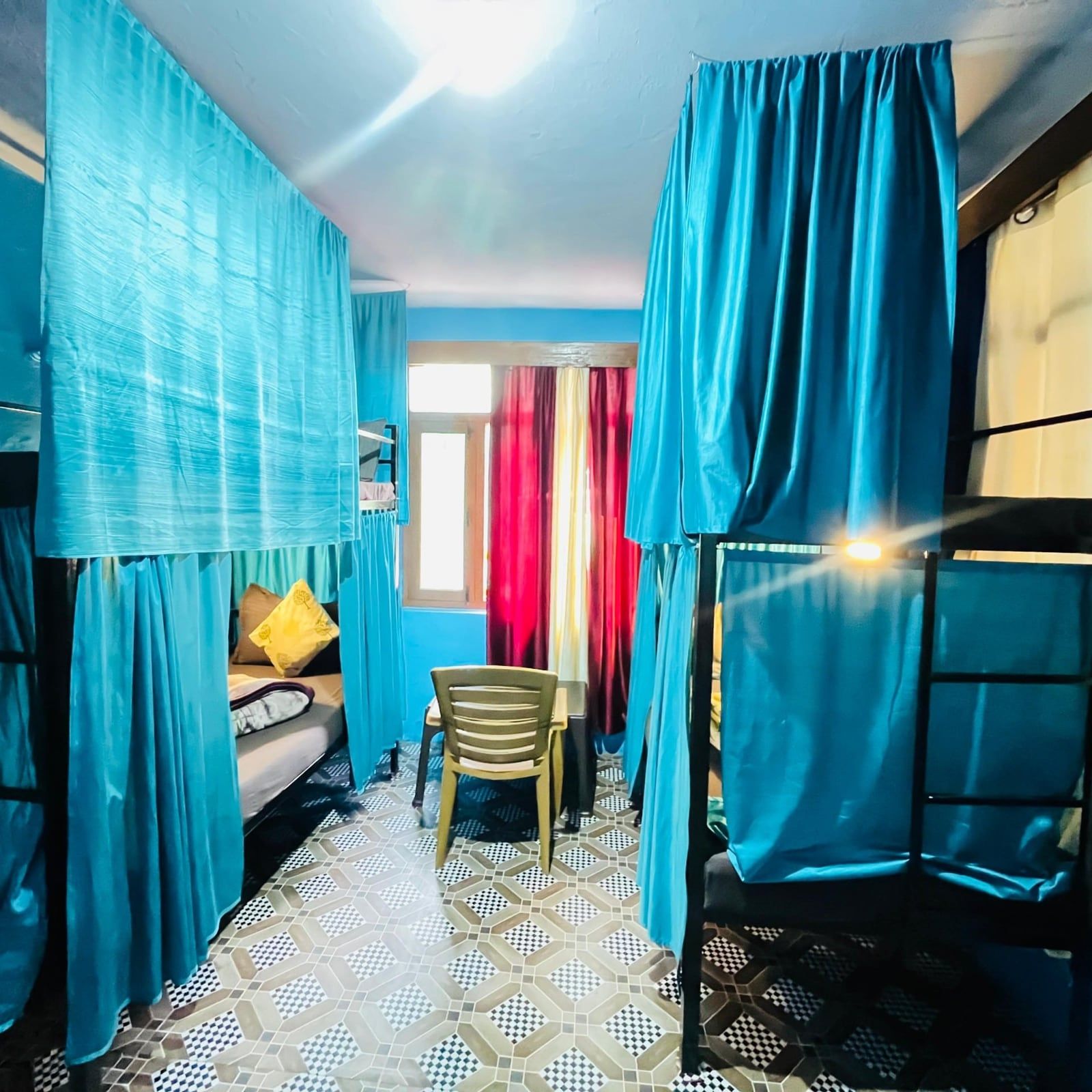 Dorm with bunk beds, each behind its own teal curtain