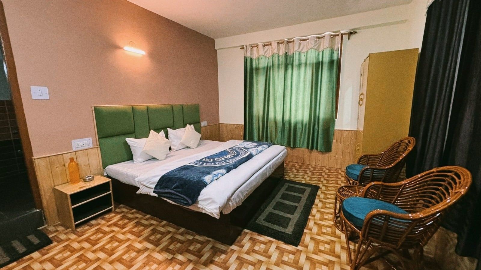 Double room with a green headboard, wicker chairs and green curtains