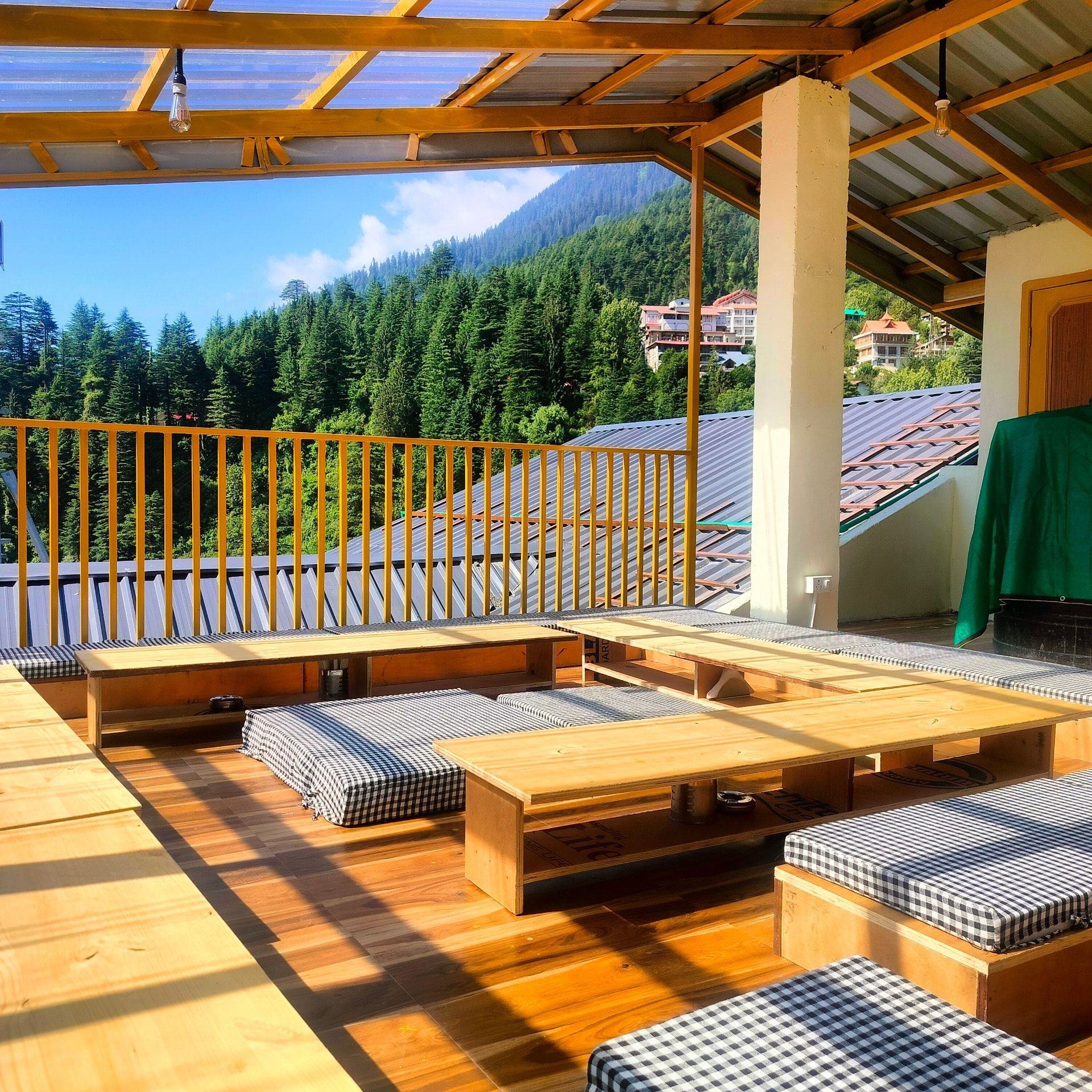Rooftop terrace with low tables, checked cushions and deodar forest beyond