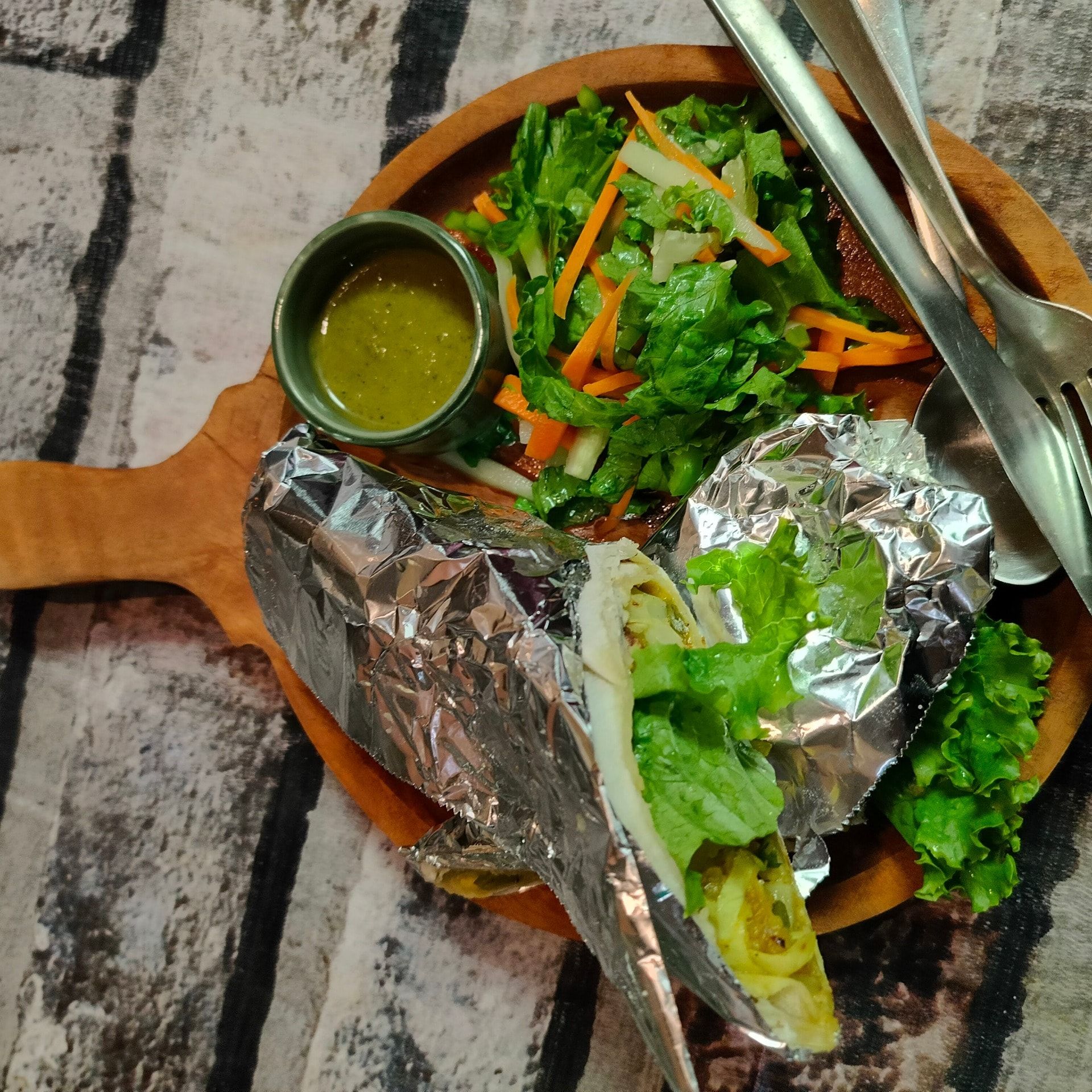 A wrap in foil with salad and green chutney